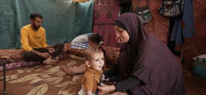 Duaa Abu Sabha is dressing her child in clothes inside her tent in the Al-Mawasi area of Khan Yunis Governorate.